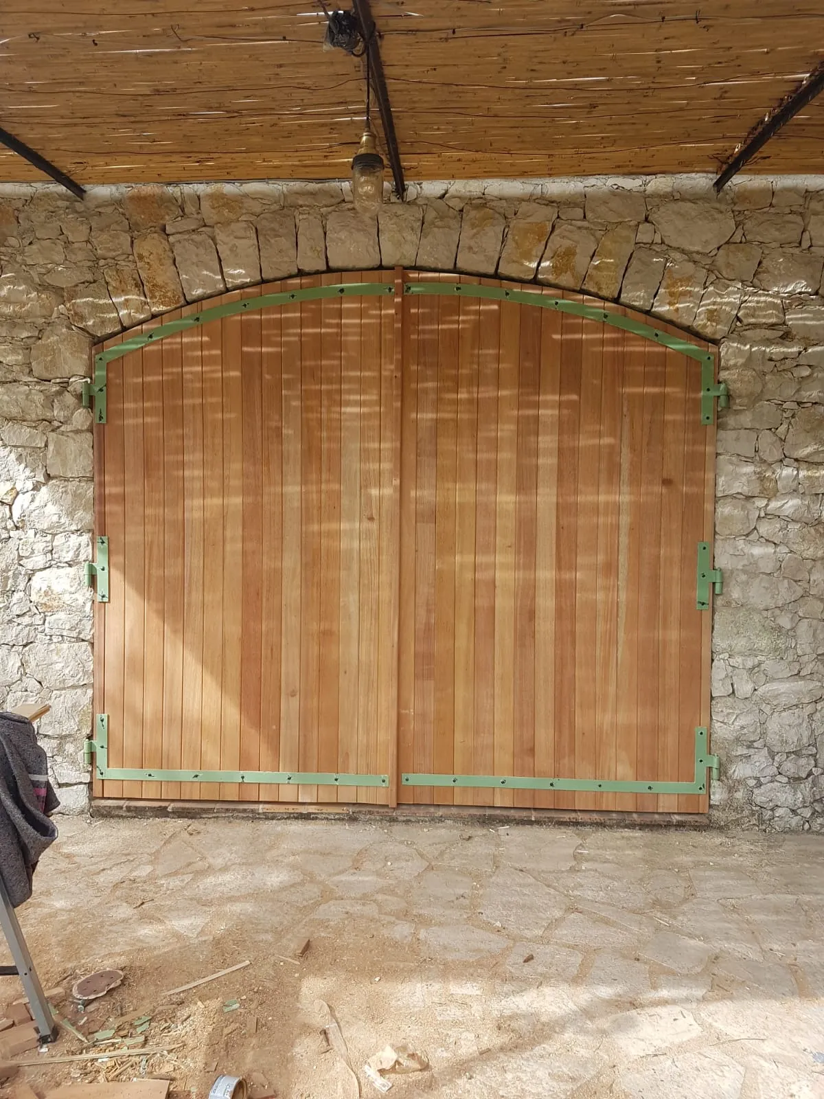 Porte de garage en bois à deux vantaux sous un arc en pierre