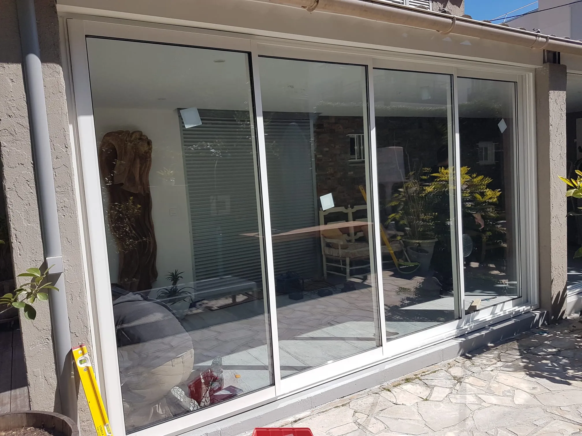 Baie coulissante aluminium blanc à quatre vantaux posée en façade