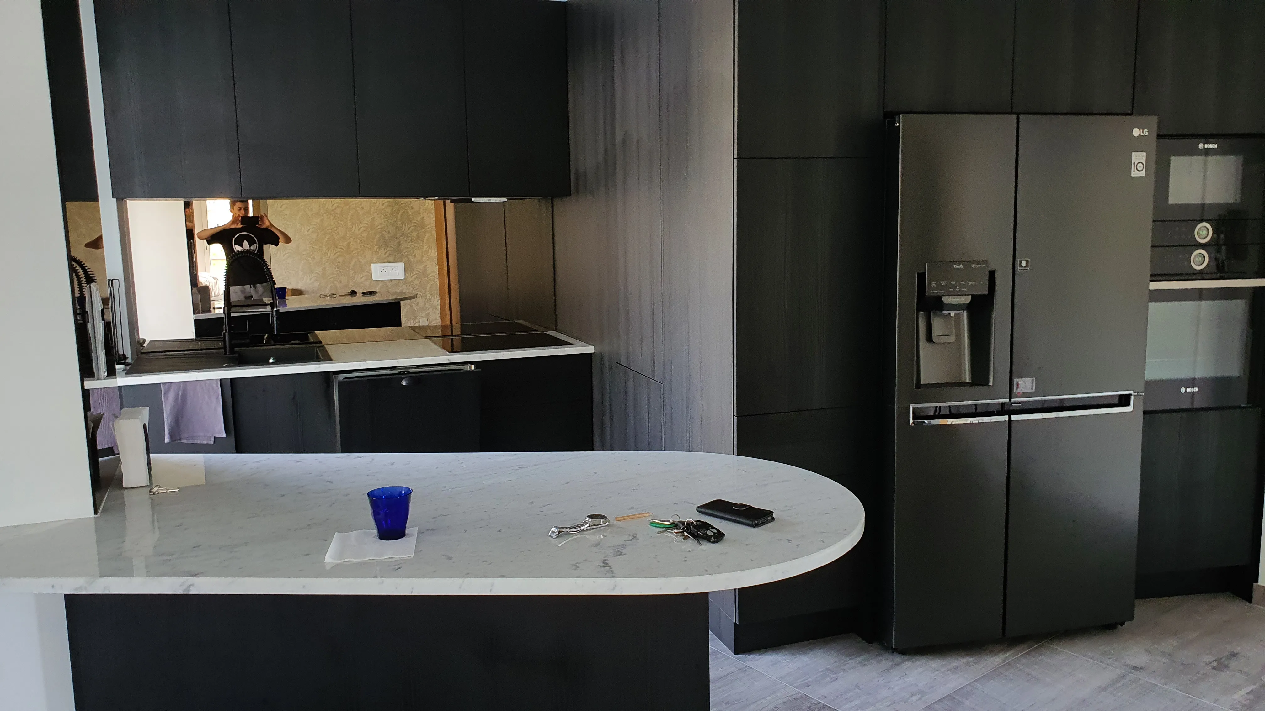 Cuisine à îlot, façades noires et plan de travail en marbre blanc