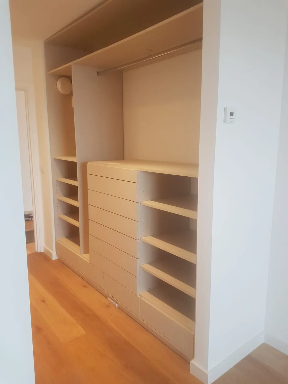 Dressing sur mesure en bois clair encastré : penderie, tiroirs et étagères
