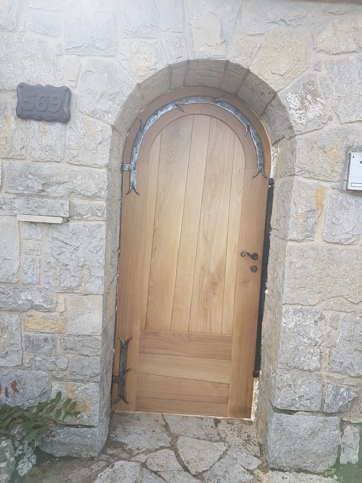 Porte d'entrée cintrée en chêne à pentures forgées