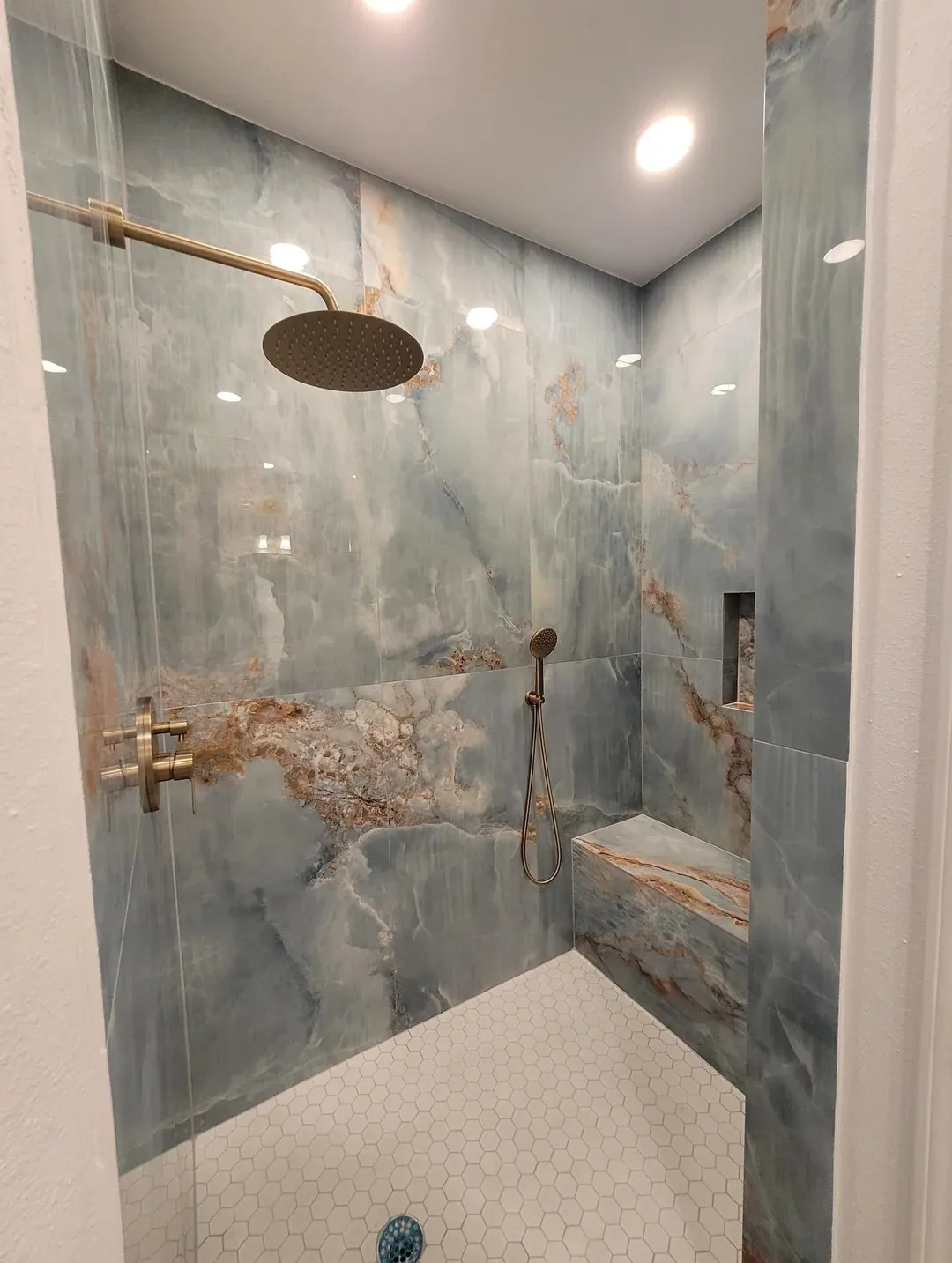 Douche à l'italienne, carrelage effet onyx et robinetterie dorée