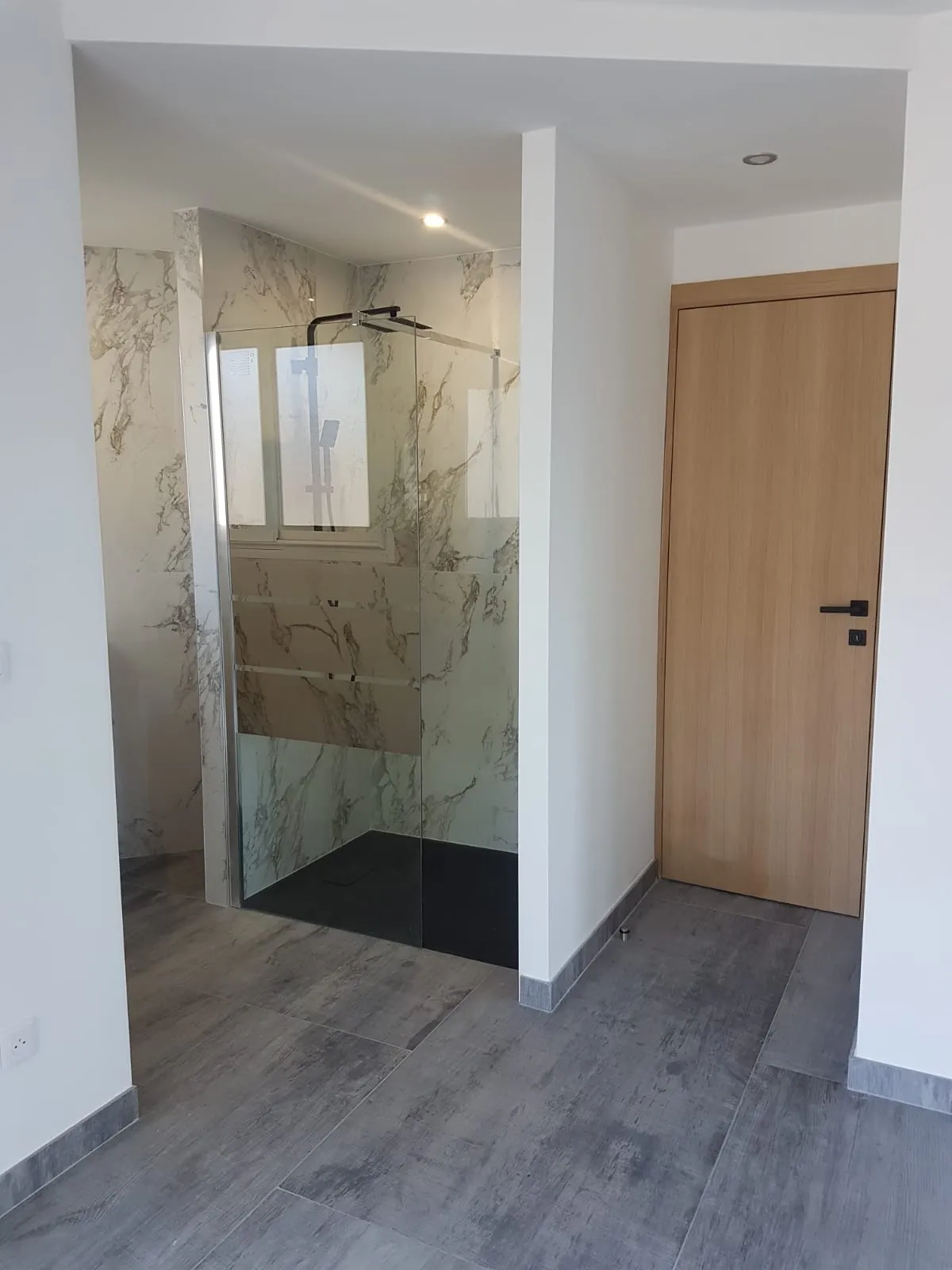 Douche à l'italienne en marbre, receveur noir et porte en bois
