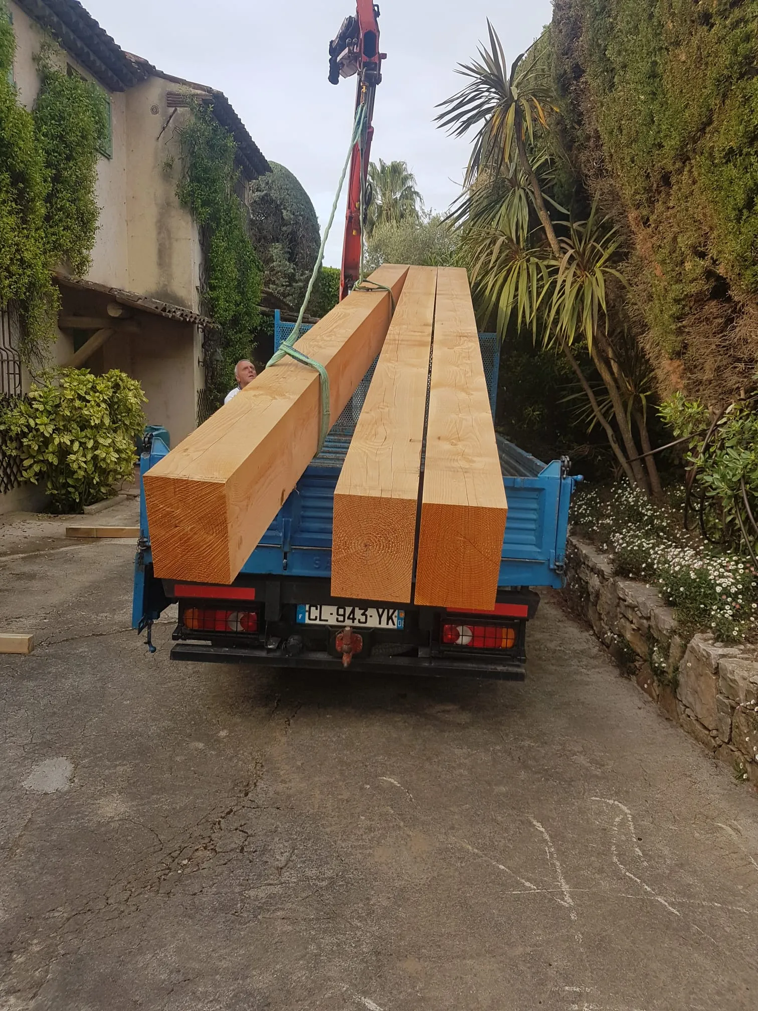 Livraison de poutres en bois massif sur chantier par camion-grue